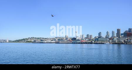 Ein Hubschrauber, der über Elliott Bay vor der Skyline von Seattle und der historischen Space Needle fliegt. Seattle. Stockfoto