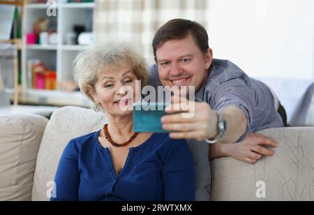 Junger Mann nimmt Selfie auf dem Smartphone mit seiner Mutter Stockfoto