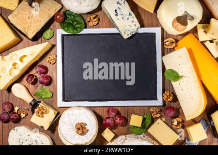 Verschiedene Käsesorten. Käseplatte mit verschiedenen Käse, mit Trauben, Nüssen, Käsemesser und Gewürzen, Holzhintergrund Kopierraum Stockfoto
