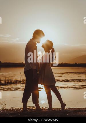 Ein junges romantisches Paar, das den atemberaubenden Sonnenuntergang über einem ruhigen Gewässer beobachtet. Stockfoto