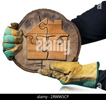 Hände mit Arbeitshandschuhen, die einen Querschnitt eines Baumstammes mit einem Holzhaus aus Puzzleteilen halten. Isoliert auf weißem Hintergrund. Stockfoto