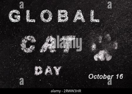 Global Cat Day Banner. Poster „Internationaler Katzentag“. Urlaubskonzept mit weißer Kreidetypografie und Fußabdruck von Katzenpfoten isoliert auf Schwarz Stockfoto