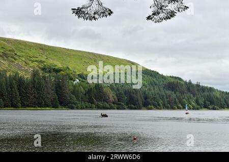 Pontsticill Reservoir im Brecon Beacons National Park mit zwei Booten und einem Hügel und Bäumen um ihn herum. Es ist der zweite Stausee Stockfoto