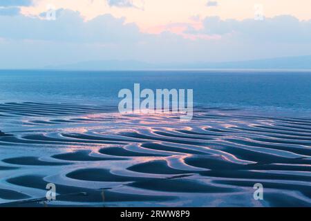 Sandmuster der Mikoshiorai-Küste, untergehende Sonne und Meer Stockfoto