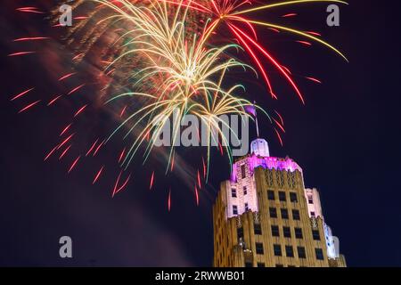 Rot-grün-goldenes Feuerwerk am 4. Juli über dem violett beleuchteten Lincoln Tower in Fort Wayne Stockfoto