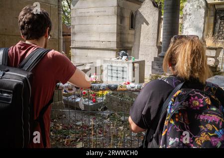 Zwei Touristen besuchen das Grab von Jim Morrison, dem Sänger und Frontmann der berühmten Band The Doors, der 1971 im Alter von 27 Jahren in Paris starb. Pere Lachaise C Stockfoto