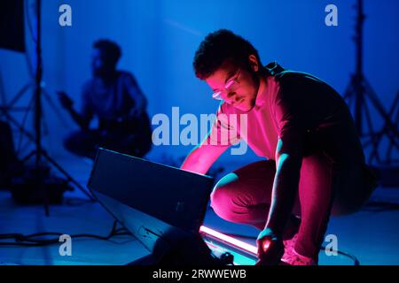 Professioneller Bediener, der das Licht vor der Aufnahme im Studio einstellt Stockfoto