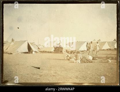 Blick auf einen Campingplatz mit einer großen Anzahl von Zelten und Sandsäcken übereinander. Es gibt mehrere indische Männer, die im Vordergrund hocken oder stehen. Wahrscheinlich ein Militärlager während des 1. Weltkriegs. Originaltitel: Indian Camp. Stockfoto