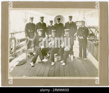 Porträtfotografie, aufgenommen an Deck eines Schiffes, einer Gruppe uniformierter Schiffsoffiziere. Auf der Rückseite des Fotos wird der Name der Royal Indian Navy genannt, aber der Name des Schiffes ist nicht angegeben. George Ellis Wood ist durch ein X auf der rechten Seite des Fotos gekennzeichnet. Auf der Rückseite steht: G E Wood Royal Indian Navy (1. R stehend) um 1900. Stockfoto