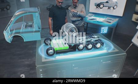 Zwei männliche Automobilingenieure entwickeln einen neuen umweltfreundlichen Lkw mit Elektromotor mit futuristischem Virtual-Reality-Hologramm-Modell. 3D-Computergrafik moderner Fahrzeugentwicklung. VFX-Animation. Stockfoto