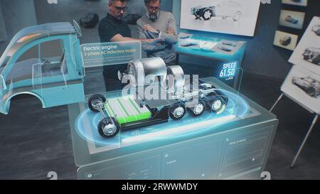 Zwei männliche Automobilingenieure entwickeln einen neuen umweltfreundlichen Lkw mit Elektromotor mit futuristischem Virtual-Reality-Hologramm-Modell. 3D-Computergrafik moderner Fahrzeugentwicklung. VFX-Animation. Stockfoto