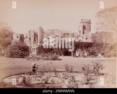 Blick auf die Ruinen der britischen Residenz mit überwachsenen Pflanzen. Sie wurde während der indischen Rebellion von 1857 ruiniert. Im Vordergrund stehen Landschaftsgärten und ein junger indischer Junge hockt an einem Blumenbeet. Der Titel lautet: Lucknow Residency. Stockfoto