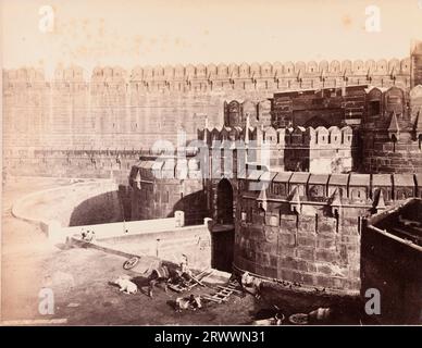 Blick auf das Western Delhi Gate und die befestigten roten Sandsteinmauern rund um das Agra Fort. Im Vordergrund sitzt eine Gruppe indischer Arbeiter mit Holzkarren, Ochsen und einem Pferd an den Mauern des Grabens. Auf negativ eingeschrieben: Frith's Series. 3073. Das Fort; Agra. Die Bildunterschrift lautet: The Walls, Agra. Stockfoto