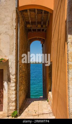 Ein schmaler Durchgang, der von einer Straße hinunter zum Ufer im historischen Zentrum der mittelalterlichen Küstenstadt Rovinj in Istrien, Kroatien, führt Stockfoto