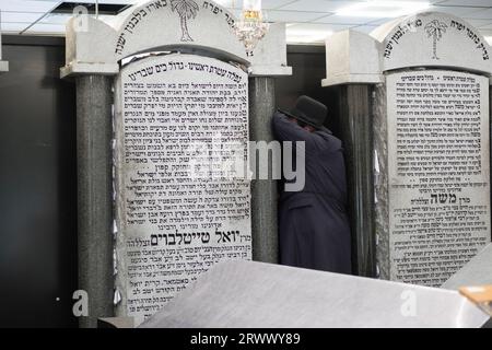 Ein orthodoxer jüdischer Mann betet neben den Grabsteinen der letzten beiden Satmarer Großrabbiner. Auf dem Old Satmar Cemetery in Kiryas Joel, Orange Cty, NY Stockfoto