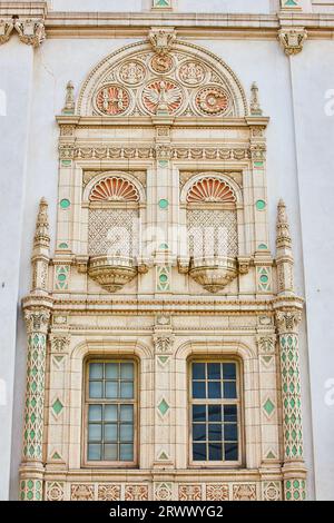 Nahaufnahme der hübschen, goldfarbenen und pastellgrünen, kunstvollen Mauer und Fenster des Rathausgebäudes Stockfoto