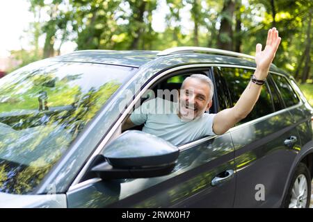 Ein netter Mann begrüßt jemanden während der Fahrt Stockfoto
