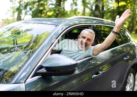 Ein netter Mann begrüßt jemanden während der Fahrt Stockfoto