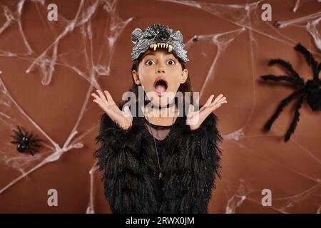 Close up Junges Mädchen sieht entsetzt aus mit erhobenen Händen auf braunem Hintergrund, Halloween-Konzept Stockfoto