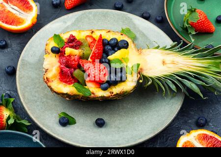 Obstsalat mit Erdbeeren, Kiwis, Beeren und Orangen, serviert in einer halben Ananas. Gesunde Ernährung Stockfoto