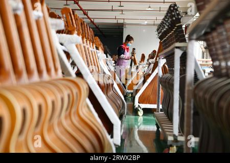 (230921) -- GUIYANG, 21. September 2023 (Xinhua) -- ein Mitarbeiter arbeitet an einer Gitarre in einer Werkstatt des Zheng'an Guitar Culture Industry Park im Kreis Zheng'an, Provinz Guizhou im Südwesten Chinas, 25. März 2020. Nach mehr als 200 aufwändigen und langwierigen Herstellungsverfahren kommen exquisit gefertigte Gitarren als charakteristische Produkte des Zheng'an County in der südwestlichen chinesischen Provinz Guizhou heraus. Diese Kunstwerke werden dann über die China-Europa-Güterzüge, den Wassertransport und andere Mittel in die Welt verteilt. UM MIT "Economic Watch: Chinesische Gitarrenindustrie reitet auf Wave o Stockfoto