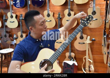 (230921) -- GUIYANG, 21. September 2023 (Xinhua) -- Zhao Jianfeng stellt eine Gitarre in einem Showroom der Natasha Musical Instrument Manufacturing Co., Ltd. Im Kreis Zheng'an, Provinz Guizhou im Südwesten Chinas, 1. September 2023 ein. Nach mehr als 200 aufwändigen und langwierigen Herstellungsverfahren kommen exquisit gefertigte Gitarren als charakteristische Produkte des Zheng'an County in der südwestlichen chinesischen Provinz Guizhou heraus. Diese Kunstwerke werden dann über die China-Europa-Güterzüge, den Wassertransport und andere Mittel in die Welt verteilt. MIT "Economic Watch: Chinesische Gitarrenindustrie reitet Stockfoto