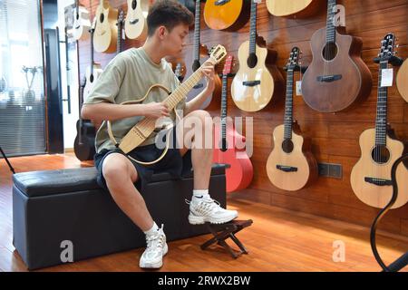 (230921) -- GUIYANG, 21. September 2023 (Xinhua) -- Ein Kunde probiert eine Gitarre in einem Showroom der Natasha Musical Instrument Manufacturing Co., Ltd. In Zheng'an County, Südwestchinesische Provinz Guizhou, 1. September 2023. Nach mehr als 200 aufwändigen und langwierigen Herstellungsverfahren kommen exquisit gefertigte Gitarren als charakteristische Produkte des Zheng'an County in der südwestlichen chinesischen Provinz Guizhou heraus. Diese Kunstwerke werden dann über die China-Europa-Güterzüge, den Wassertransport und andere Mittel in die Welt verteilt. UM MIT "Economic Watch: Chinesische Gitarrenindustrie reitet auf wa Stockfoto