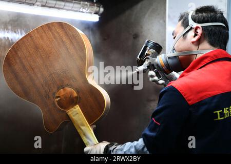 (230921) -- GUIYANG, 21. September 2023 (Xinhua) -- Ein Arbeiter spritzt Farbe auf eine Gitarre in einer Werkstatt des Zheng'an Guitar Culture Industry Park im Kreis Zheng'an, Provinz Guizhou im Südwesten Chinas, 25. März 2020. Nach mehr als 200 aufwändigen und langwierigen Herstellungsverfahren kommen exquisit gefertigte Gitarren als charakteristische Produkte des Zheng'an County in der südwestlichen chinesischen Provinz Guizhou heraus. Diese Kunstwerke werden dann über die China-Europa-Güterzüge, den Wassertransport und andere Mittel in die Welt verteilt. UM MIT "Economic Watch: Chinesische Gitarrenindustrie reitet auf wa Stockfoto