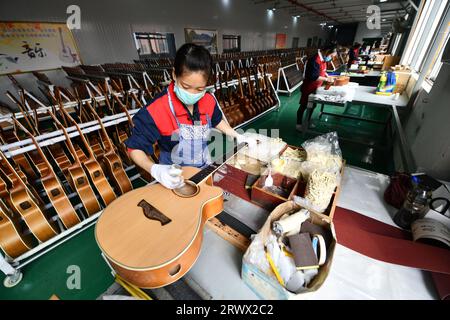 (230921) -- GUIYANG, 21. September 2023 (Xinhua) -- ein Mitarbeiter arbeitet an einer Gitarre in einer Werkstatt des Zheng'an Guitar Culture Industry Park im Kreis Zheng'an, Provinz Guizhou im Südwesten Chinas, 25. März 2020. Nach mehr als 200 aufwändigen und langwierigen Herstellungsverfahren kommen exquisit gefertigte Gitarren als charakteristische Produkte des Zheng'an County in der südwestlichen chinesischen Provinz Guizhou heraus. Diese Kunstwerke werden dann über die China-Europa-Güterzüge, den Wassertransport und andere Mittel in die Welt verteilt. UM MIT "Economic Watch: Chinesische Gitarrenindustrie reitet auf Wave o Stockfoto