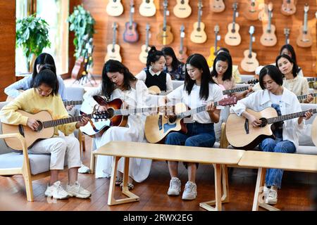 (230921) -- GUIYANG, 21. September 2023 (Xinhua) -- Menschen lernen Gitarre in einem Showroom der Natasha Musical Instrument Manufacturing Co., Ltd. Im Kreis Zheng'an, Provinz Guizhou im Südwesten Chinas, 13. Mai 2022. Nach mehr als 200 aufwändigen und langwierigen Herstellungsverfahren kommen exquisit gefertigte Gitarren als charakteristische Produkte des Zheng'an County in der südwestlichen chinesischen Provinz Guizhou heraus. Diese Kunstwerke werden dann über die China-Europa-Güterzüge, den Wassertransport und andere Mittel in die Welt verteilt. UM ZU GEHEN MIT "Economic Watch: Chinesische Gitarrenindustrie reitet auf W Stockfoto