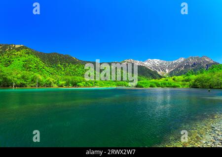 The Hotaka mountain range with lingering snow from Taisho Pond in clear weather Stock Photo