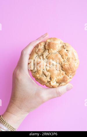 Eine Frau, die einen hausgemachten Erdnussbutter-Chip-Keks im New Yorker Stil hält. Es ist ein großer Keks mit einer knusprigen äußeren Kruste und einer weichen Mitte. Stockfoto