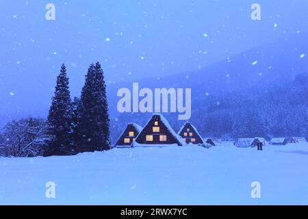 Shirakawa-Go mit Schneefall und Fensterbeleuchtung im Gassho-zukuri Village mit abendlichem Blick Stockfoto