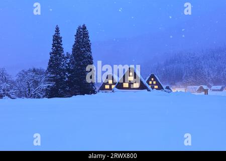 Shirakawa-Go mit Schneefall und Fensterbeleuchtung im Gassho-zukuri Village mit abendlichem Blick Stockfoto
