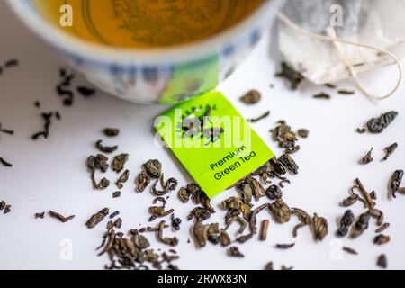 Lose grüne Teeblätter und Teebeutel mit einer Tasse grünem Tee in weiß isoliert. Gesundheitsgetränk, gesundes Lifestyle-Konzept. Stockfoto