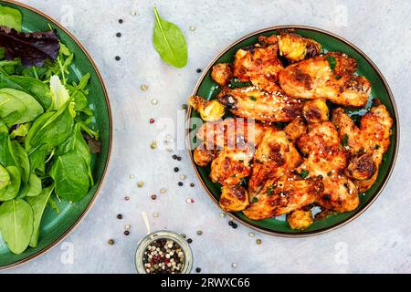 Würzige Hähnchenflügel mit Gemüse und grünem Salat. Draufsicht Stockfoto