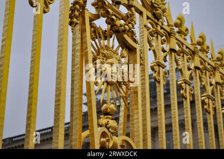 Ein Seitenwinkel des Sonnenkönigs-Symbols auf einem kunstvoll verzierten goldenen Tor um das Schloss von Versailles Stockfoto