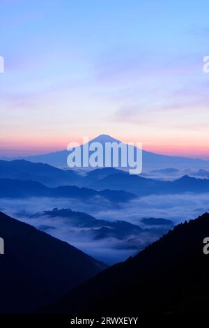 Mt. Fuji seen beyond the sea of clouds and mountain range Stock Photo