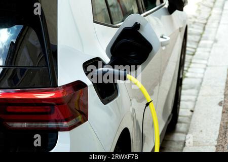 Weißes Elektroauto wird auf einem Bürgersteig aufgeladen. Frankreich Stockfoto