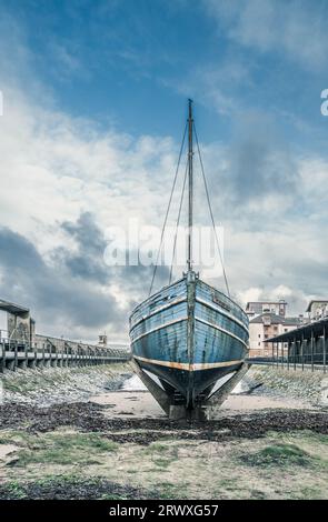 Ehemaliges Hering-Fischerboot, das im Hafen von Ayr unter bedecktem Himmel wachsam versinkt Stockfoto