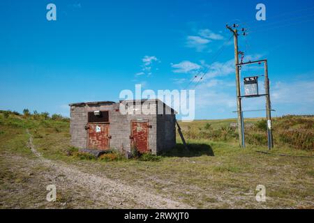 Altes Ziegelgebäude vernachlässigt auf der Landseite mit Holzpfählen verbunden mit Stromleitungen Stockfoto