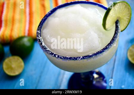 Gefrorene Margarita in einem gesalzenen, blau umrandeten Glas mit Limettenscheibe Stockfoto