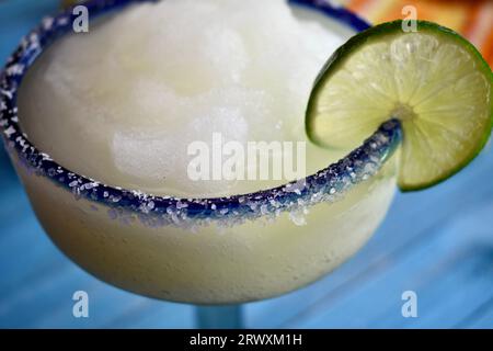 Gefrorene Margarita in einem gesalzenen, blau umrandeten Glas mit Limettenscheibe Stockfoto