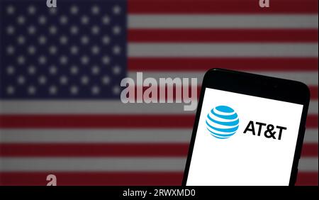 Buenos Aires, Argentinien; 08-03-2023: Das AT&T-Logo wird auf dem Bildschirm eines Mobiltelefons angezeigt, und die Flagge der Vereinigten Staaten ist im Hintergrund nicht fokussiert Stockfoto