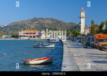 Zakynthos, Griechenland - 14. August 2016: Die Menschen laufen an der Küste des Hafens von Zante in der Nähe von angelegten kleinen Fischerbooten Stockfoto