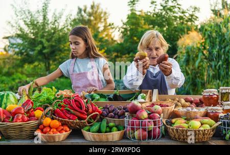 Großmutter und Enkelin verkaufen Gemüse und Obst auf dem Bauernmarkt. Selektiver Fokus. Essen. Stockfoto