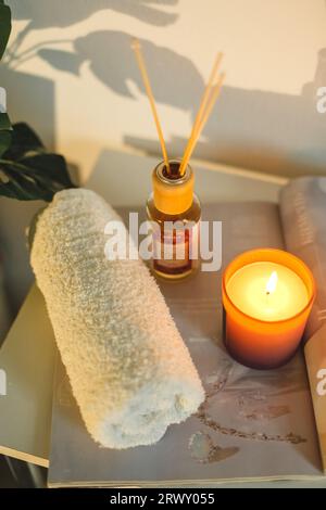 Es gibt beleuchtete Aromakerzen auf dem Tisch, Handtücher für Eingriffe liegen. Nahaufnahme. Spa-Behandlungsraum. Stockfoto