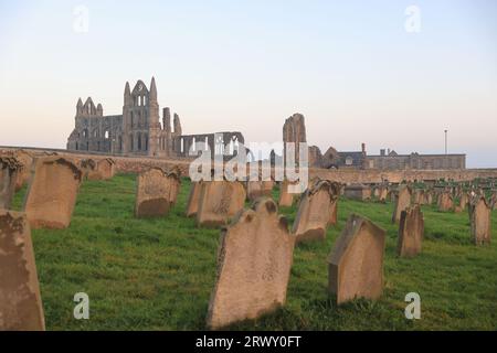 Sonnenuntergang über dem Friedhof der historischen St. Mary's Church auf dem windgepeitschten East Cliff von Whitby Abbey in North Yorkshire, Großbritannien Stockfoto