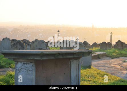 Sonnenuntergang über dem Friedhof der historischen St. Mary's Church auf dem windgepeitschten East Cliff von Whitby Abbey in North Yorkshire, Großbritannien Stockfoto