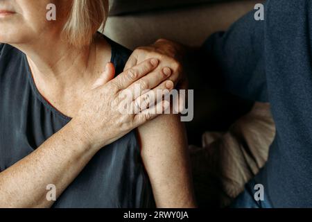 Glückliches älteres Paar. Eine ältere Frau streicht ihrem Mann die Hand, er drückt sie sanft mit seiner Hand. Nahaufnahme. Stockfoto